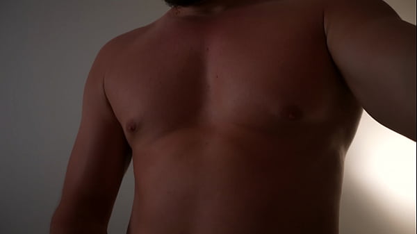 Muskulöser Kerl posiert vor der Kamera und spritzt ihm auf den Bauch